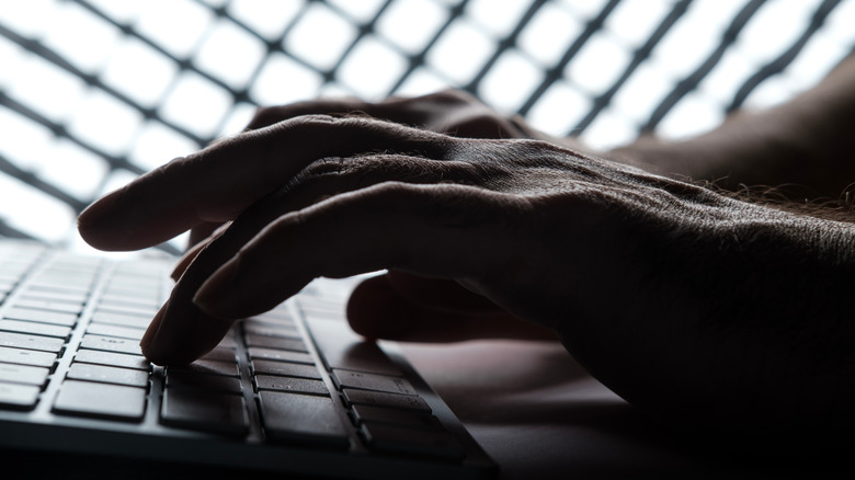 A pair of hands typing on a dark keyboard.