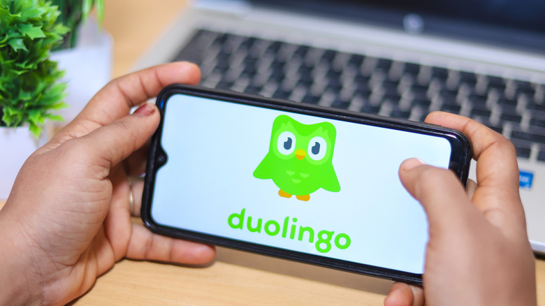 Duolingo on a phone being held over a laptop