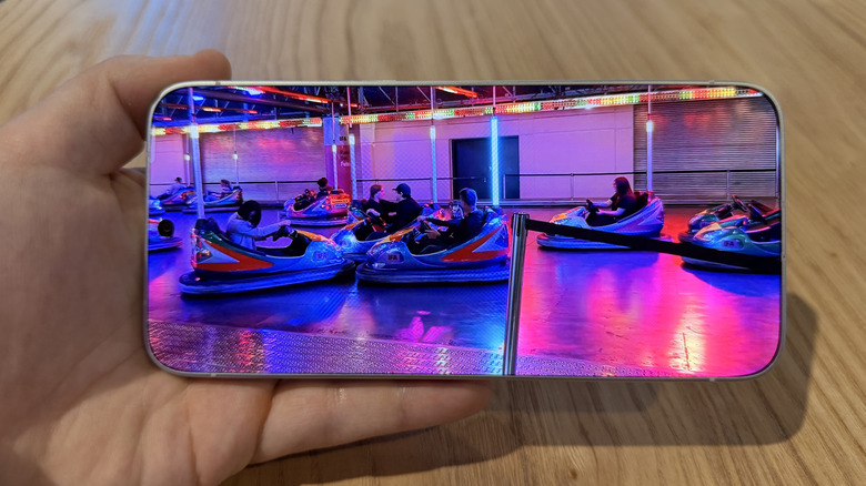 Holding the Tecno bezel-less phone to watch a video above a table