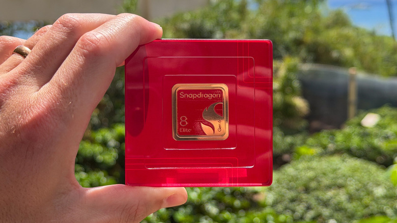 The Snapdragon 8 Elite Gen 6 mounted on a red acrylic plate with bushes shown in the background