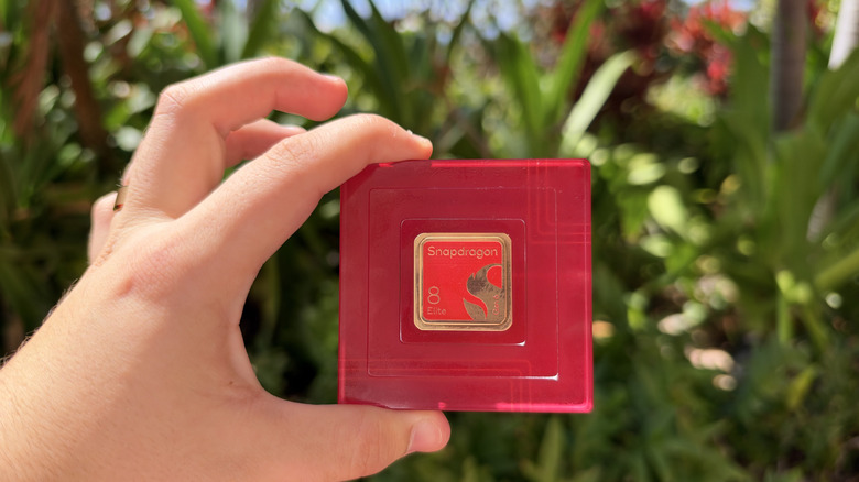Holding the Snapdragon 8 Elite Extreme Gen 6 chipset in front of plants in background