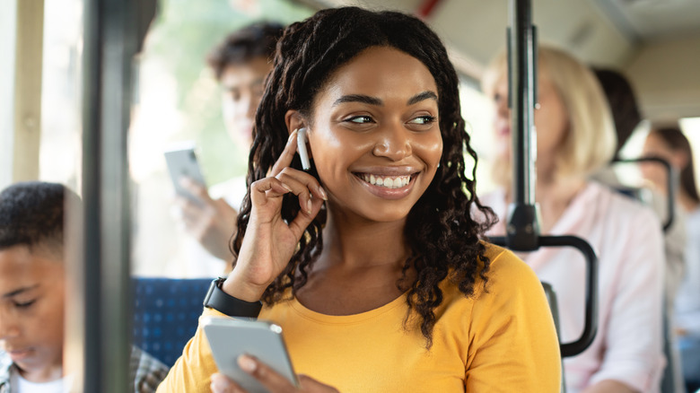 A happy woman listening to earbuds on a bus or train