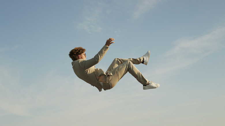 Person falling against clear blue sky