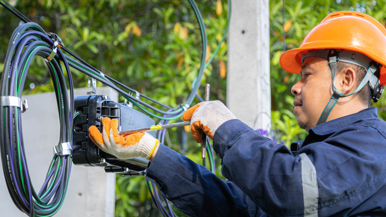 Technician working on fiber optic lines on a pole with safety gear on