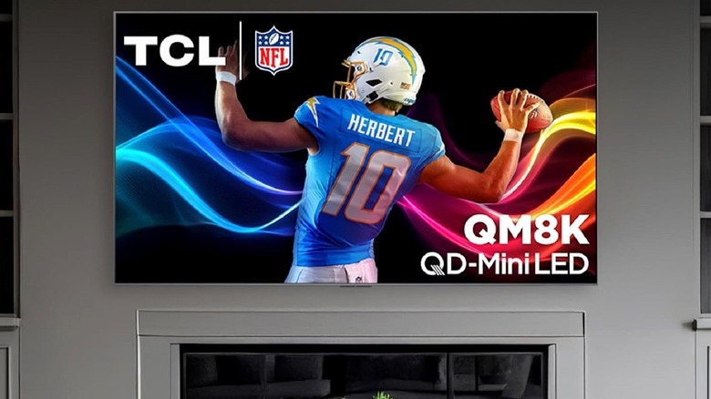 TCL QM8K smart Google TV installed on wall and mounted with football player visible onscreen.