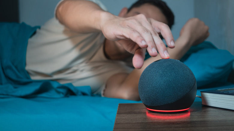A man muting an Amazon Echo dot.