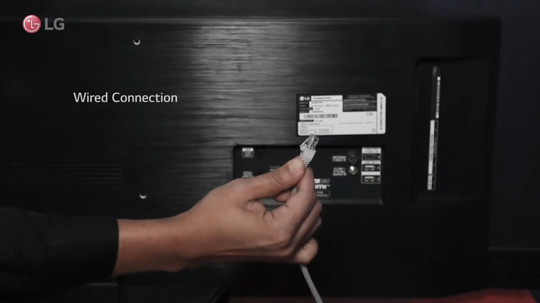 Hand holding LAN cable with LG TV in the background