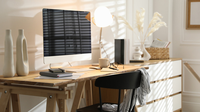 A computer on a desk in a sunny room with glare showing prominently on the monitor.