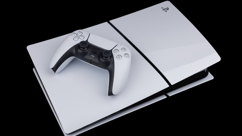 a PlayStation 5 disc slim model with a controller on top of it on a black background