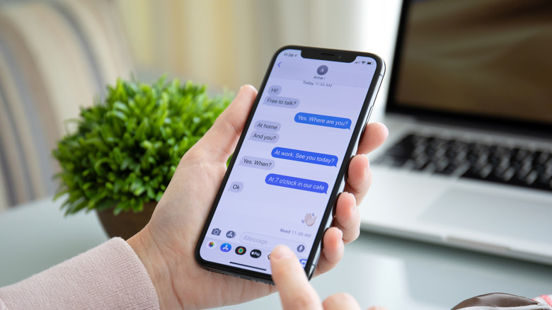 person holding iPhone with iMessage displayed on screen
