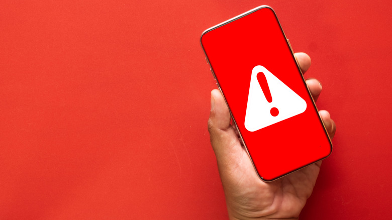 a hand holding a phone with a red security warning on it