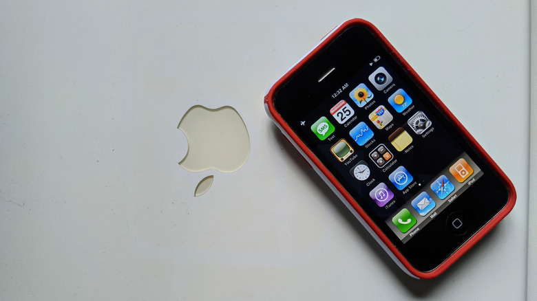 An Apple iPhone 3GS lying on top of a closed MacBook