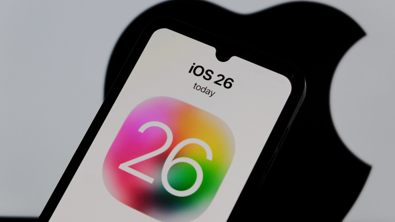 An iPhone showing iOS 26 with an Apple logo in the background.
