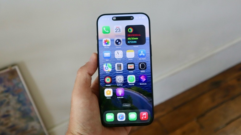 A hand holding an iPhone with the Home Screen opened up