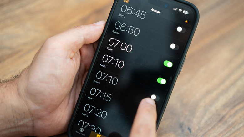 person setting alarms and turning them on on iPhone