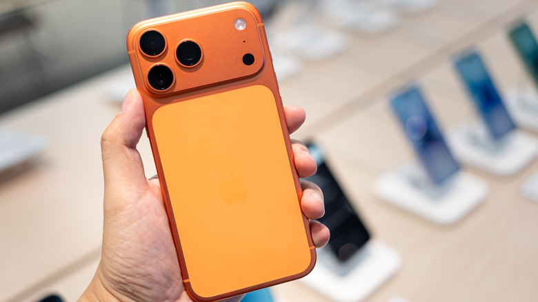 The iPhone 17 Pro Max in hand, with other iPhone models seen in the blurred background.