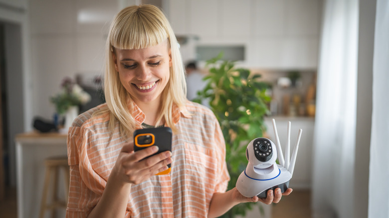 Woman holding home security camera and iPhone
