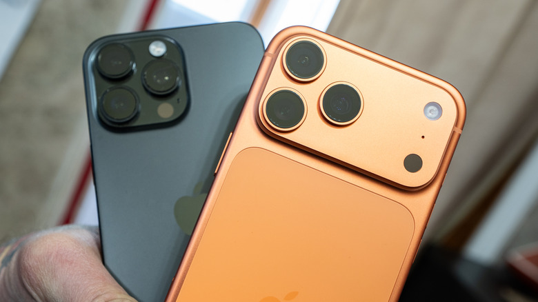 A Cosmic Orange iPhone 17 Pro sitting on top of a black iPhone 16, both phones are being held in a user's hand