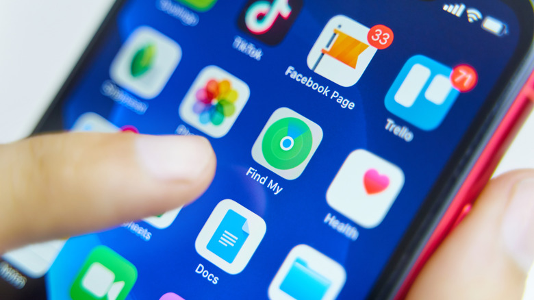 A close-up of a finger on an iPhone about to tap the Find My button.