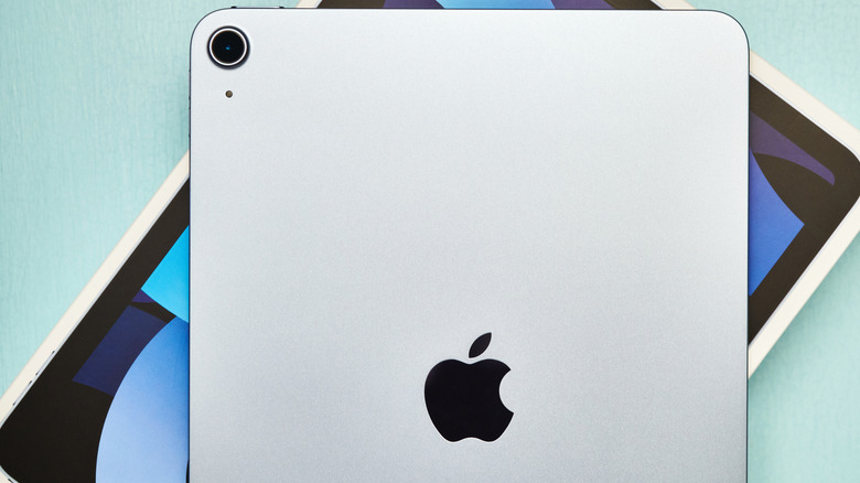 An iPad Air over its box against a light blue background