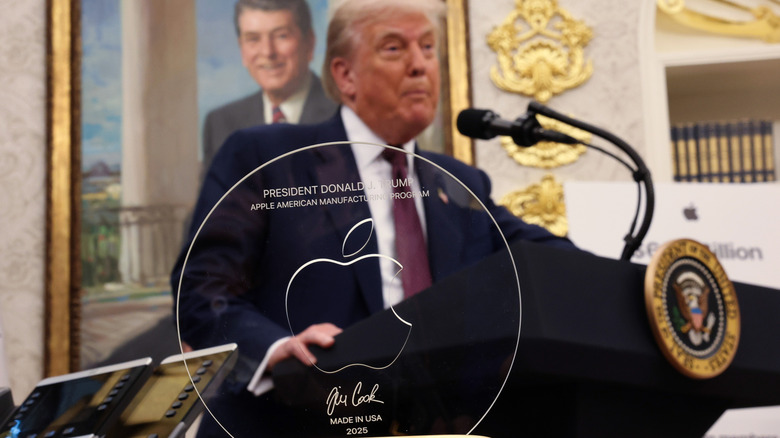 President Donald Trump speaks behind an engraved glass disc gifted to him by Apple CEO Tim Cook during an event in the Oval Office of the White House on August 6, 2025.