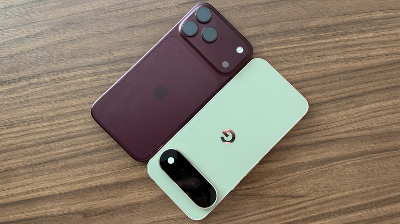 iPhone 18 Pro Max and Pixel 11 Pro XL laying next to one another diagonally on a wood table