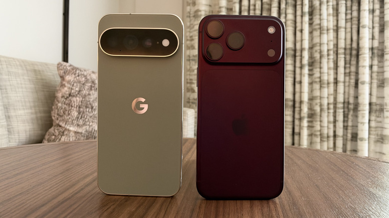 iPhone 18 Pro Max and Pixel 11 Pro XL stood upright next to each other on a wood table