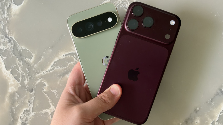 iPhone 18 Pro Max and Pixel 11 Pro XL being held in the same hand above a marble surface