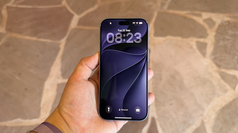 iPhone 18 Pro display being held in hand above stone tiles