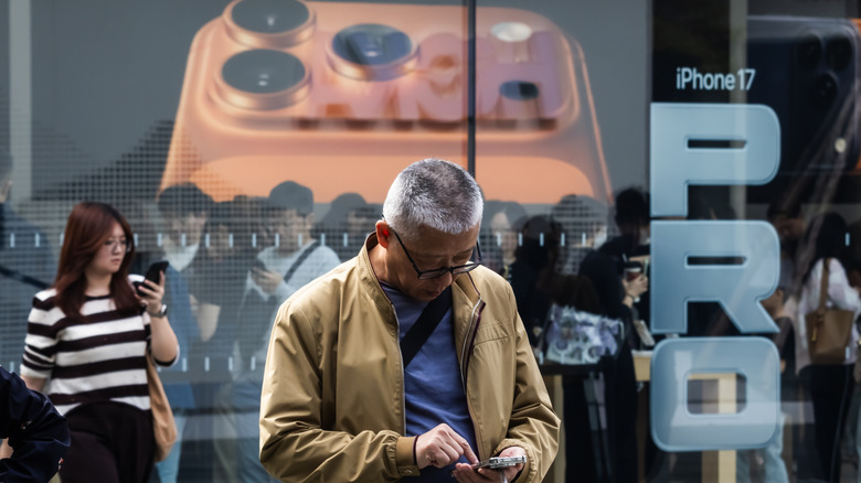 A person using an iPhone outside an Apple retail store.