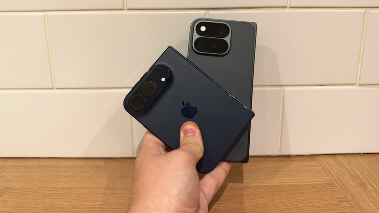 iPhone Duo and Pixel 11 Pro Fold being held together in one hand in front of white tiles