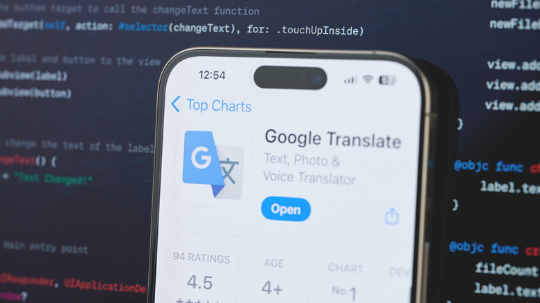 Google Translate application open on an iPhone with a screen of code in the background