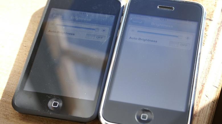 An iPhone and iPod Touch side by side on a wooden surface.