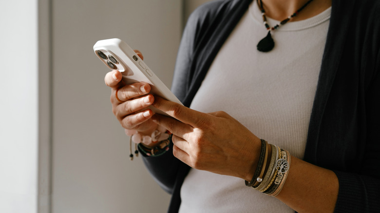 A person holding an iPhone with a white case on it