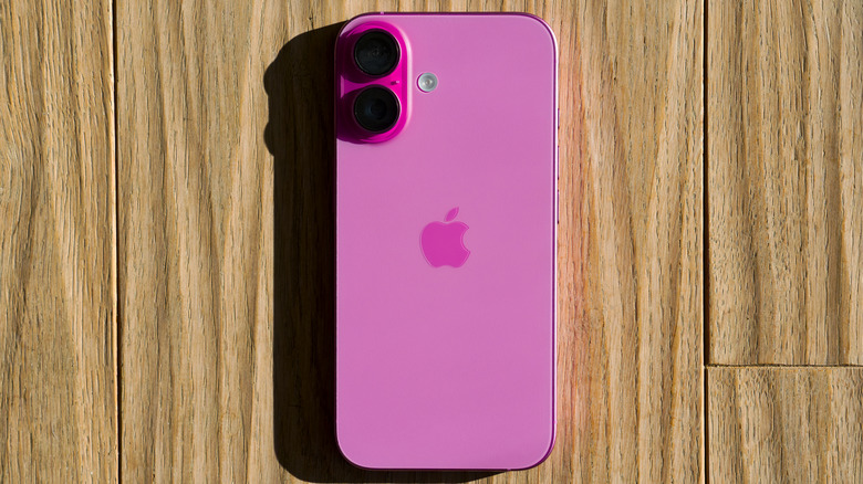 A pink iPhone sitting face down on what appears to be a wooden floor or deck