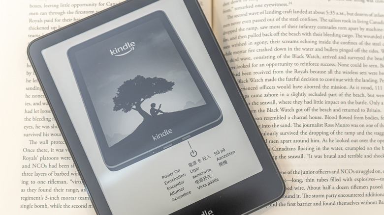 Kindle e-reader on packaging placed over an open book page.