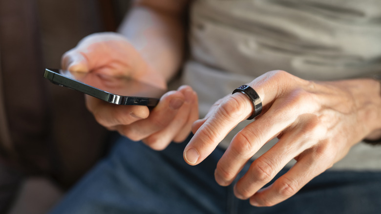 A person wearing the Samsung Galaxy Ring and holding a smartphone.