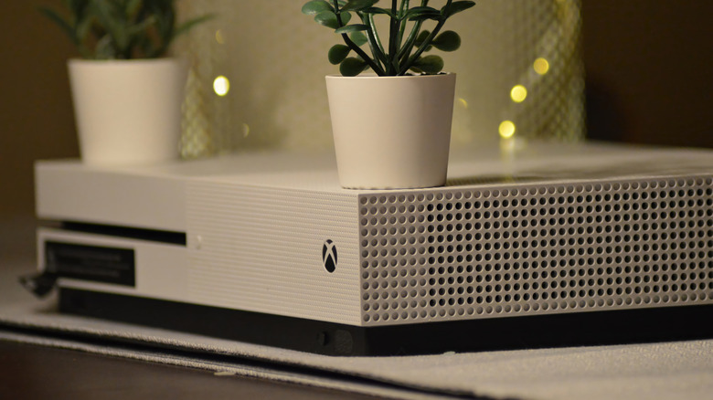 An Xbox One S Digital Edition with plants on it.
