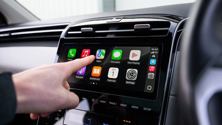 A person controlling CarPlay apps in the car.