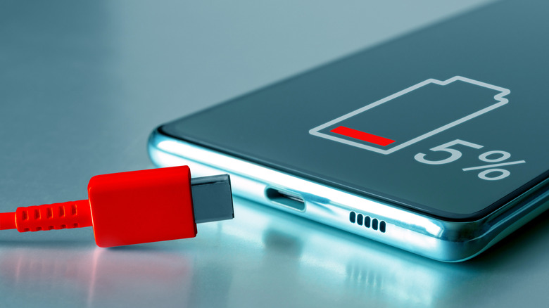 a phone with low battery and a red USB-C charging cable