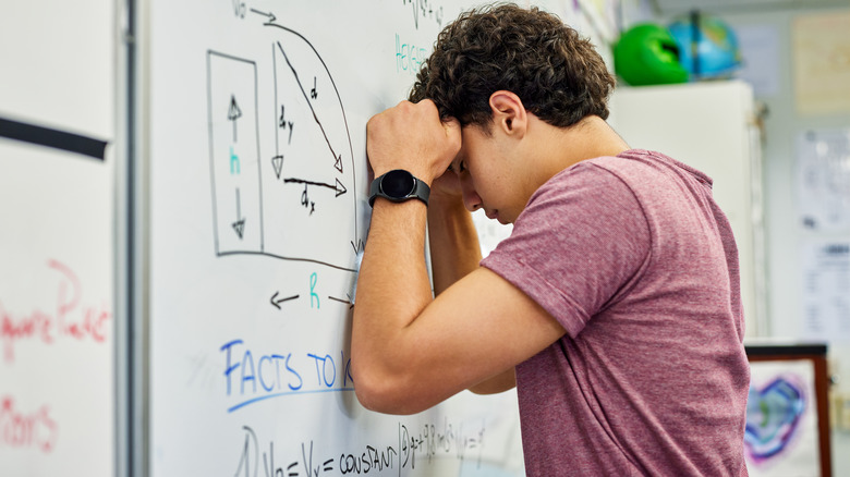 a young man struggling to understand math equations on a whiteboard