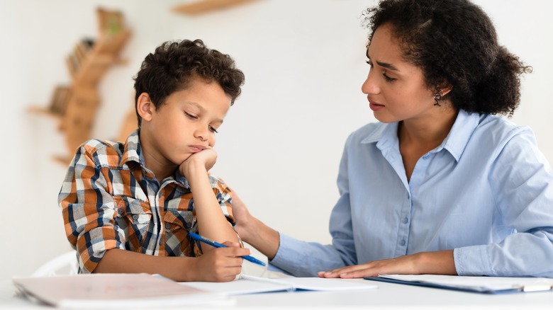 a young kid struggling to learn in school with a teacher helping him