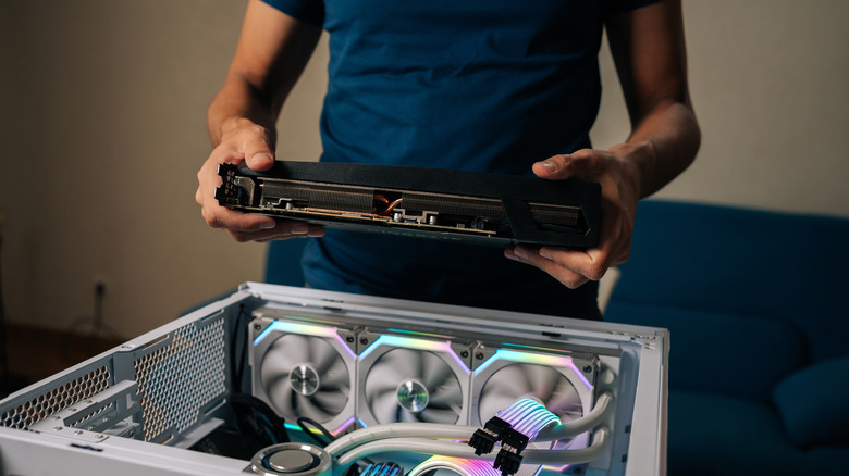 Man building a PC, installing a graphics card into the case