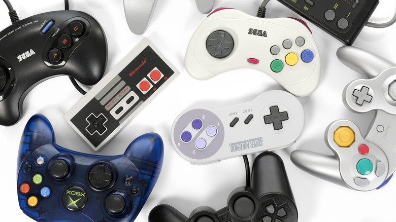 Old gaming controllers surrounding each other on a white surface