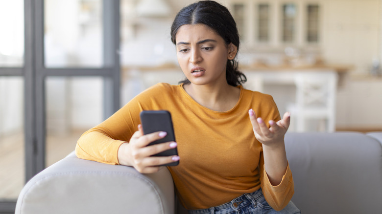 a frustrated woman looking at her phone