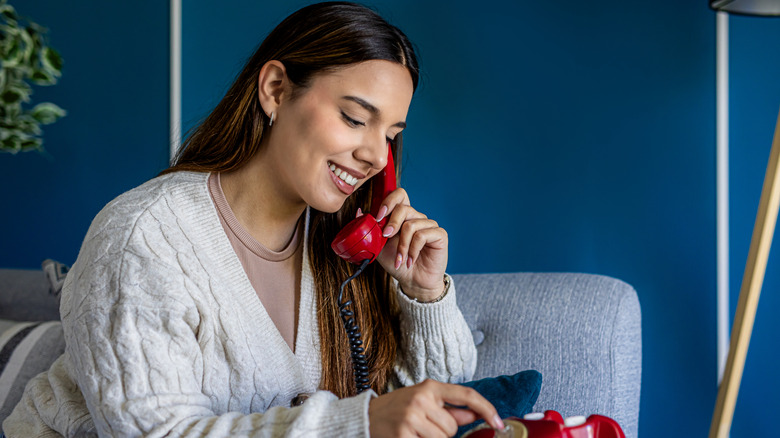 A woman makes a call using a rotary phone.