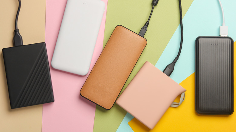 A variety of power banks in front of a colorful construction paper background.