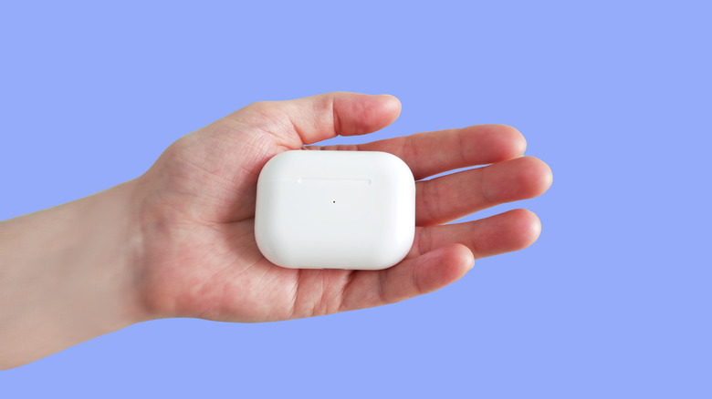Someone holding AirPods while in their charging case