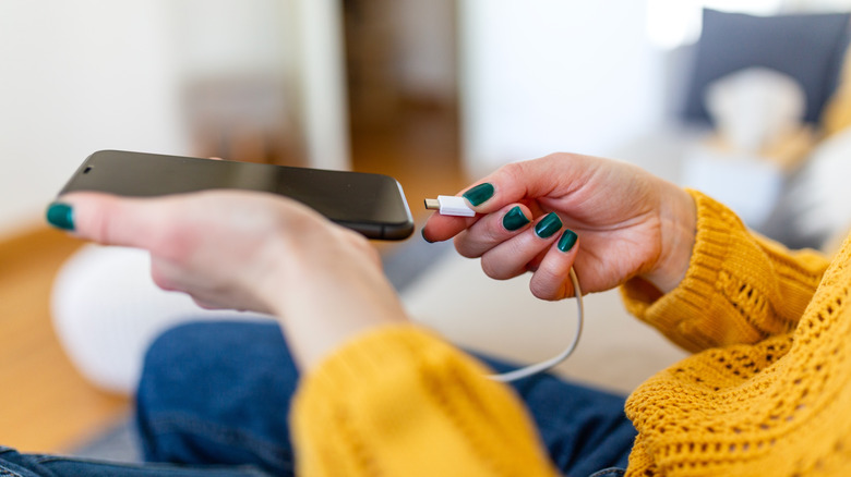 A woman connecting a USB cable to a phone