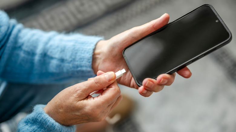 A person connecting a USB cable to a phone